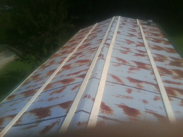 Rusted metal roof panels with new wood purlins before replacement — Storm Damage Roof Repair in Karthaus by Roofing Brothers