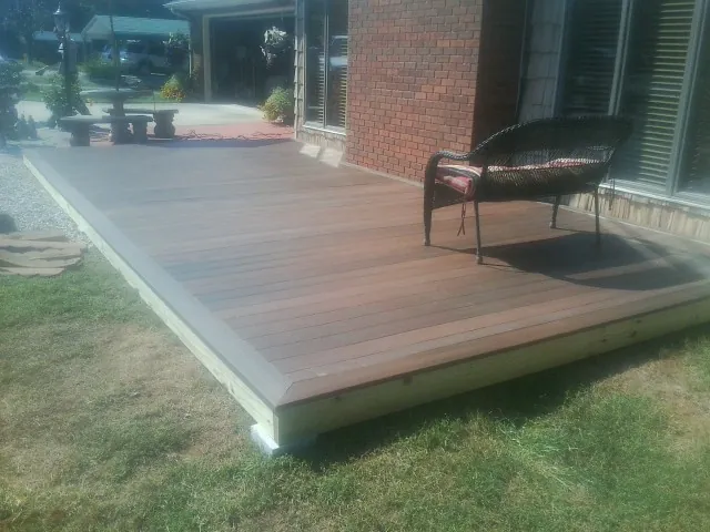 New wood deck and wicker chair beside a brick house in Karthaus