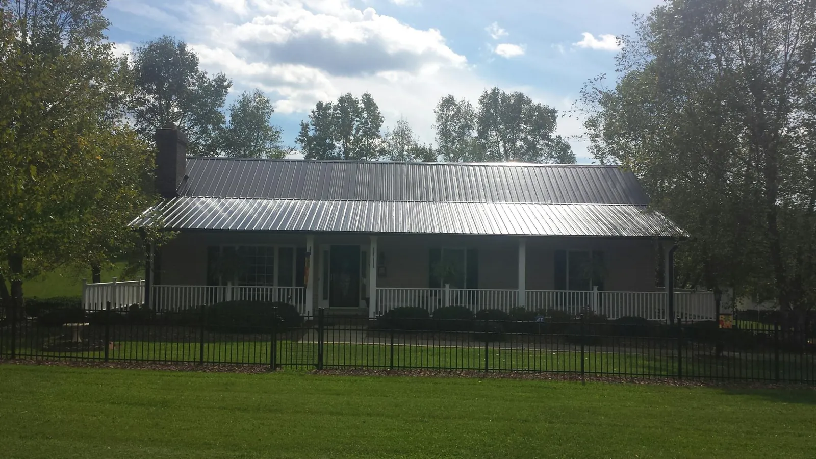 Gray metal roof on a brick ranch with a full width front porch — Gutter Guard Installation work by our crew in Karthaus