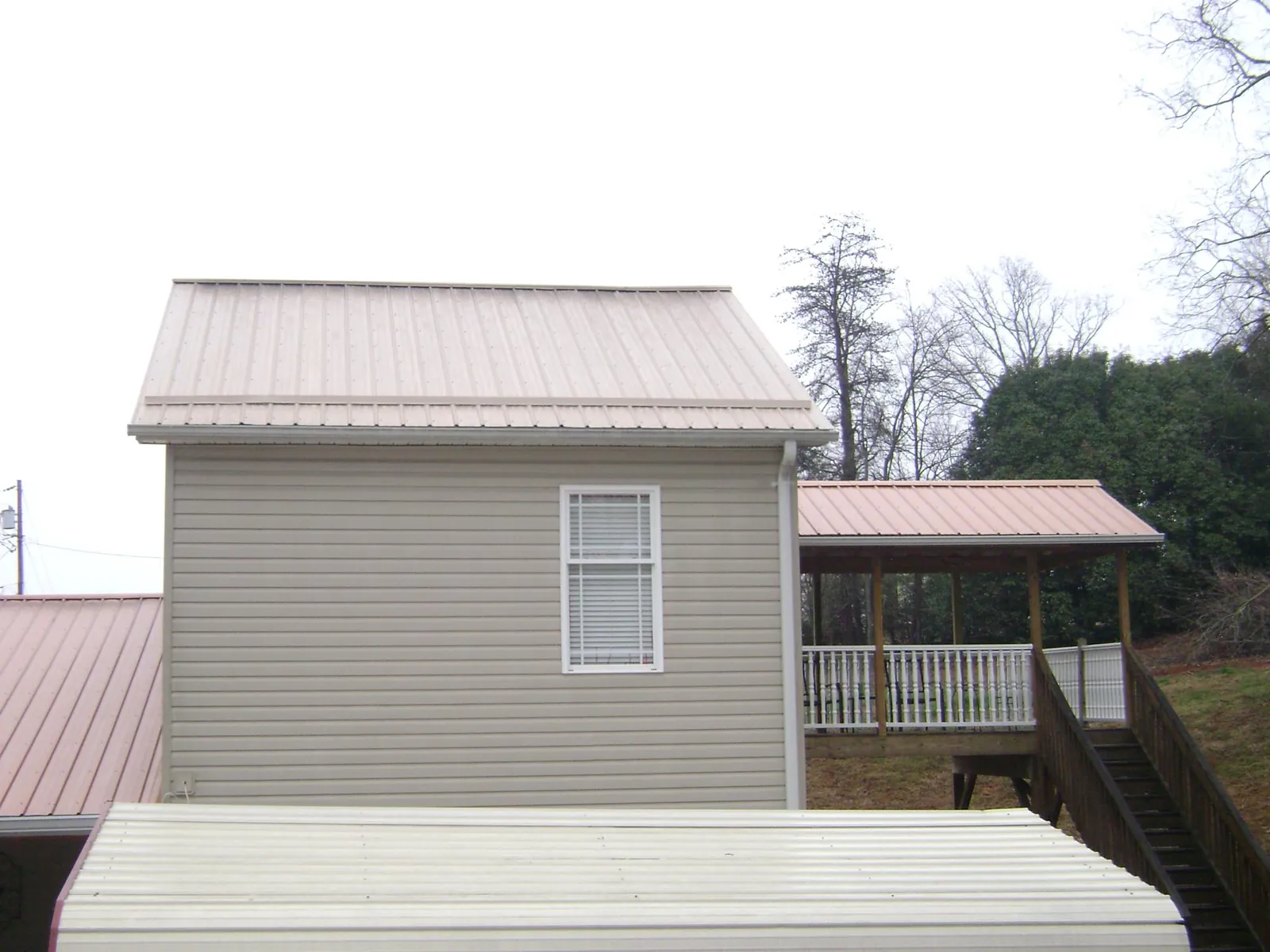 Tan metal roofs on a two story addition and attached porch, from a Roof Replacement job in Karthaus