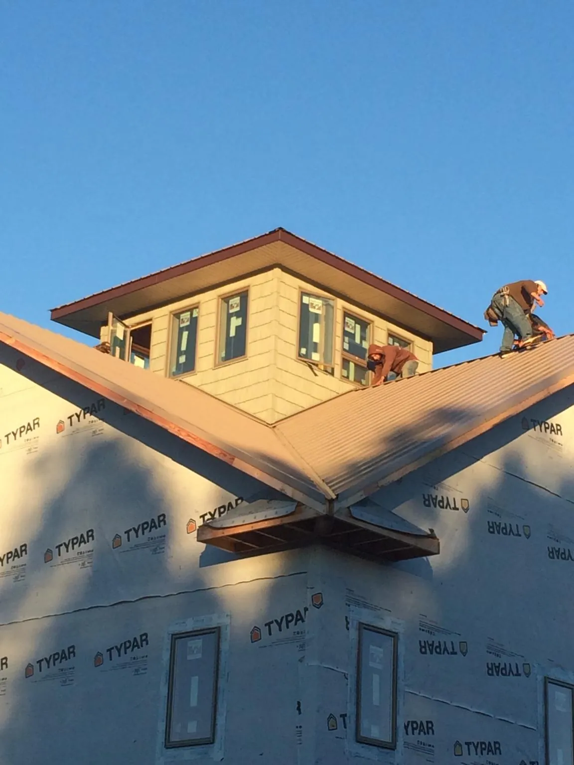 Roofers working around a rooftop cupola on a new metal roof at sunset — Roof Waterproofing in Karthaus by Roofing Brothers